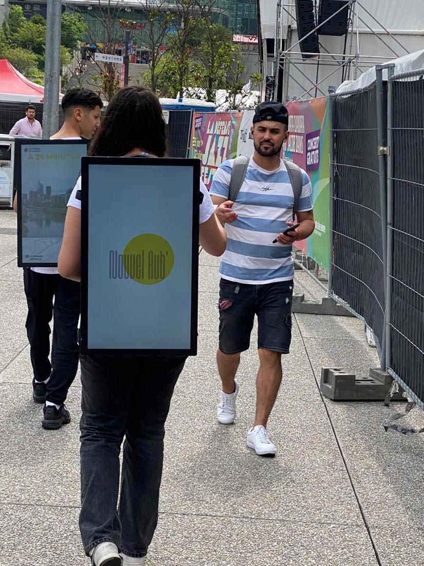Promoters with backpack screens at an outdoor event