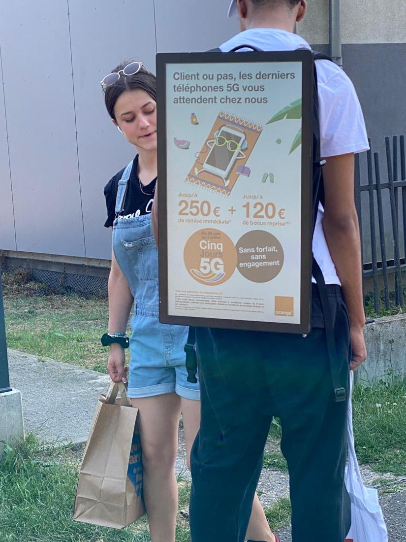 A promoter with a backpack screen talking to a passer-by