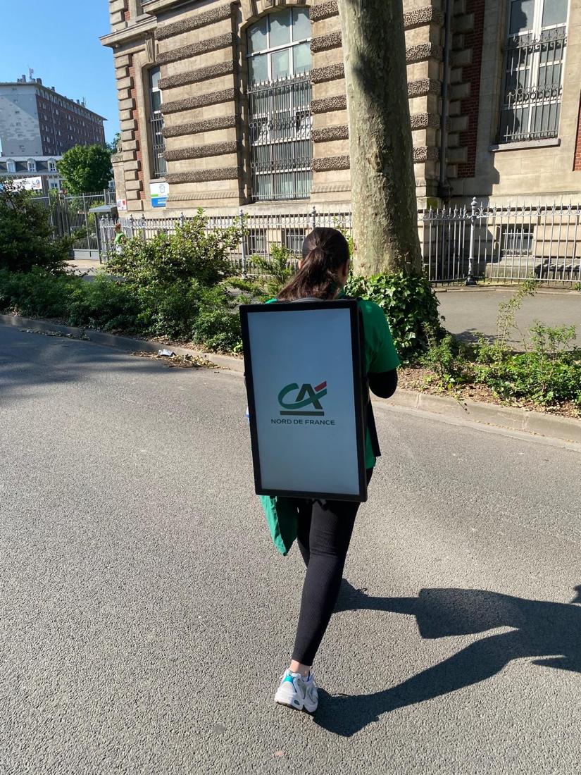 A promoter walking down a street with a backpack screen